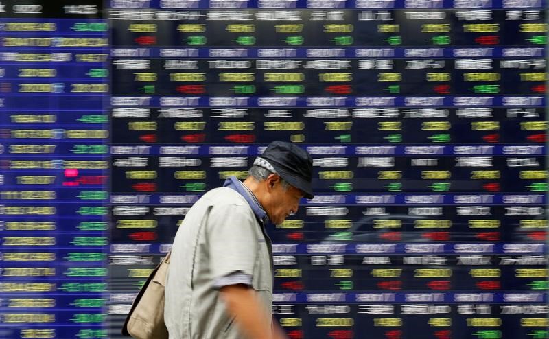 © Reuters. Tokyo, un passante davanti al tabellone elettronico di un brokerage
