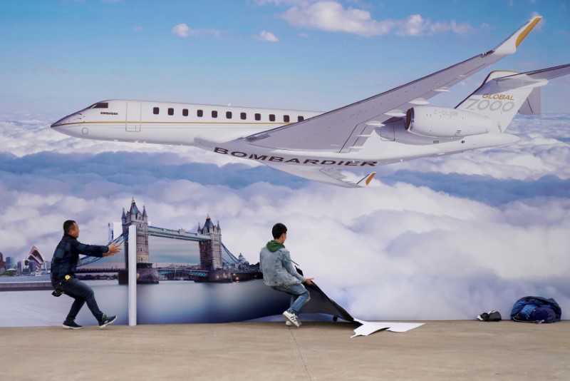 © Reuters. FILE PHOTO: Workers put up a billboard poster of the Bombardier Global 7000 aircraft at the Asian Business Aviation Conference and Exhibition (ABACE) at Hongqiao International Airport in Shanghai