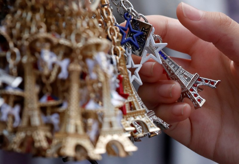© Reuters. Tourists look at Eiffel Tower keychains displayed in a souvenir shop in Paris
