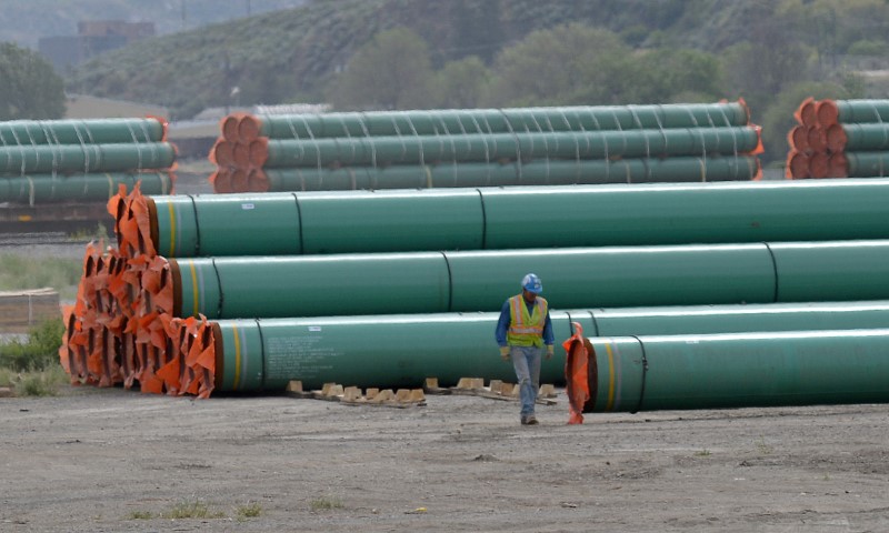 © Reuters. FILE PHOTO:    A workman walks past steel pipe to be used in the pipeline construction of the Trans Mountain Expansion Project at a stockpile site in Kamloops