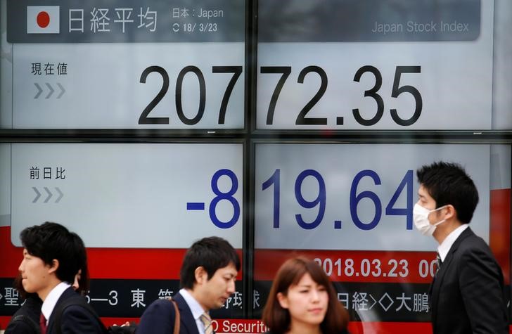 © Reuters. People walk past an electronic board showing Japan's Nikkei average outside a brokerage in Tokyo