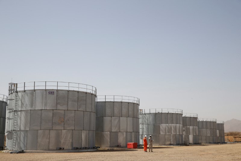 © Reuters. Workers walk past storage tanks at Tullow Oil's Ngamia 8 drilling site in Lokichar