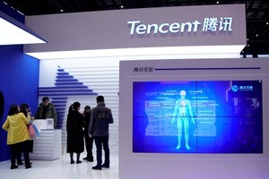 © Reuters. FILE PHOTO - Screen displaying Tencent Miying, an AI-powered medical imaging service, is seen next to visitors at the fourth World Internet Conference in Wuzhen