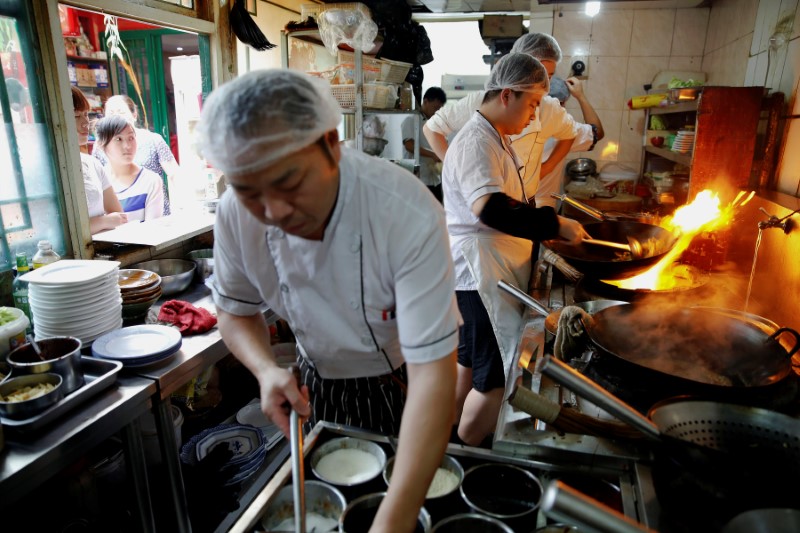 © Reuters. Staff of Zhenxiangfudi restaurant, whose manager plans to offer more beef and lamb meat dishes, if the pork price keeps rising, work at their kitchen in central Beijing