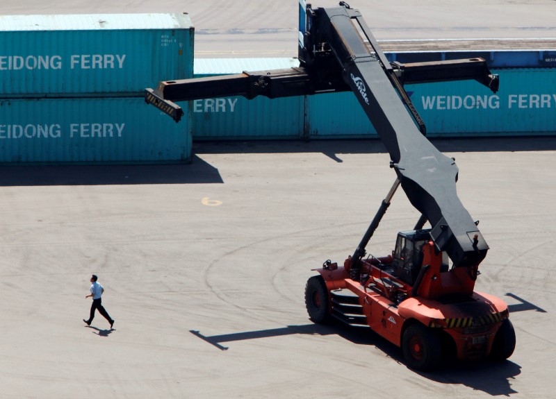 © Reuters. FILE PHOTO: A worker runs near a crane at a container port in Incheon