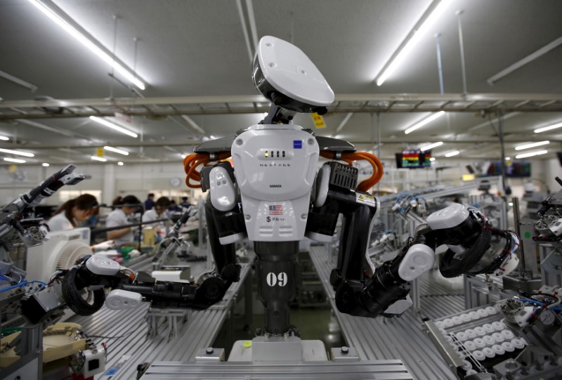 © Reuters. FILE PHOTO: A humanoid robot works side by side with employees in the assembly line at a factory of Glory Ltd., a manufacturer of automatic change dispensers, in Kazo, north of Tokyo