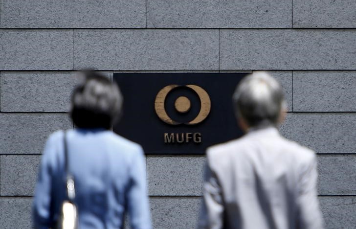 © Reuters. FILE PHOTO: A logo of the Mitsubishi UFJ Financial Group Inc. is seen between pedestrians outside its headquarters in Tokyo