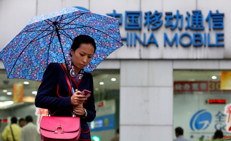 © Reuters. FILE PHOTO: A woman uses her mobile phone in front of a China Mobile office in downtown Shanghai