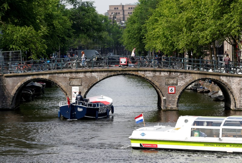 © Reuters. FILE PHOTO: Tourists boats pass on a canal in Amsterdam