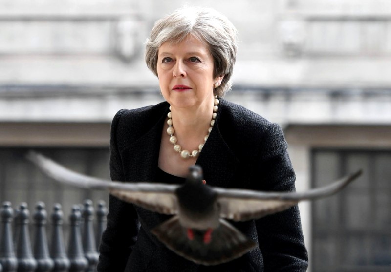 © Reuters. FILE PHOTO:  A pigeon flies ahead of Britain's Prime Minister Theresa May as she arrives at a service at St Martin-in-The Fields to mark 25 years since Stephen Lawrence was killed in a racially motivated attack, in London