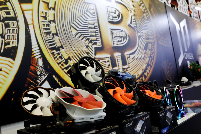 © Reuters. Cryptocurrency mining computer fans are seen in front of bitcoin logo during the annual Computex computer exhibition in Taipei