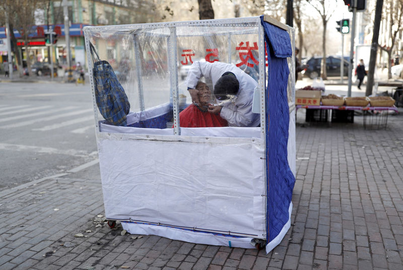 © Reuters. FILE PHOTO: A barber shaves the face of a customer at a makeshift barber shop beside a street in Shenyang