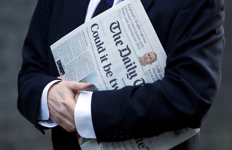 © Reuters. FILE PHOTO: A man carries a copy of The Daily Telegraph in London