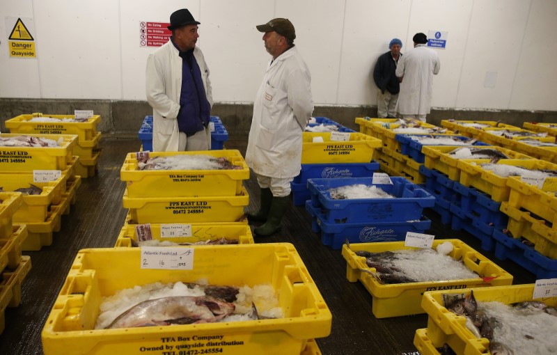 © Reuters. Fish buyers talk as they wait for the daily auction to start at the fish market in Grimsby, Britain