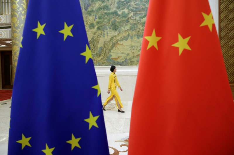 © Reuters. Funcionária passa por bandeiras da China e da União Europeia em Pequim