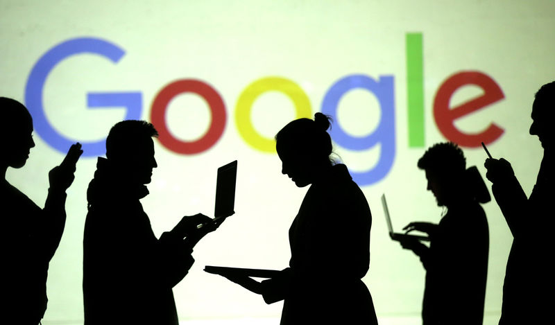 © Reuters. FILE PHOTO: Silhouettes of laptop and mobile device users are seen next to a screen projection of Google logo in this picture illustration