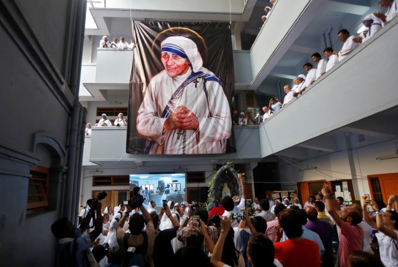 © Reuters. People sing a prayer song in front of a large banner of Mother Teresa on her death anniversary in Kolkata