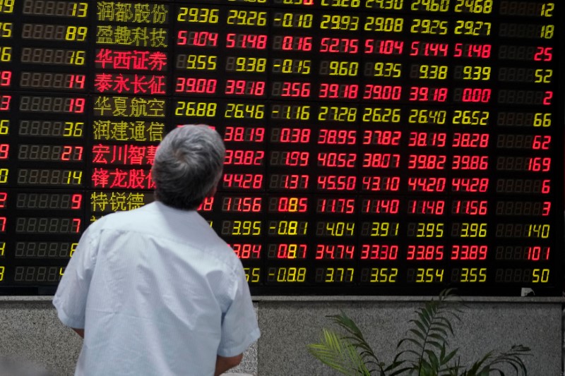© Reuters. A man looks at an electronic board showing stock information at a brokerage house in Shanghai, China