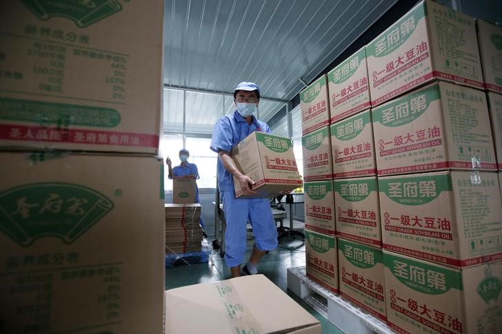 © Reuters. Un trabajador transporta cajas de aceite de soja embotellado con soja importada de EEUU en una planta en China