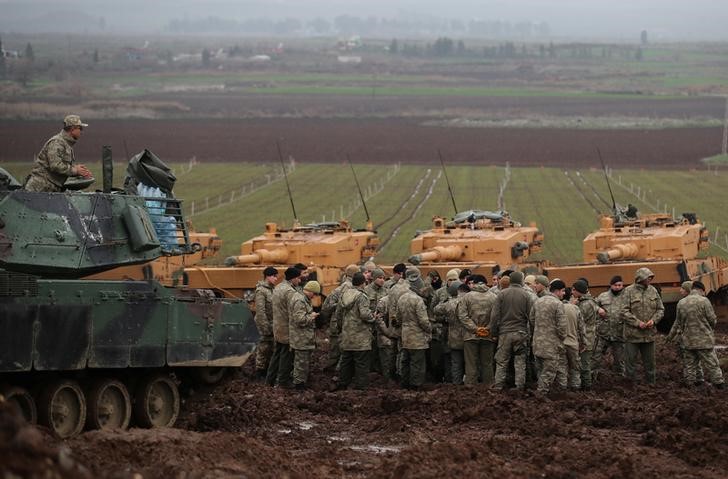 © Reuters. Turkish soldiers gather next to their tanks near the Turkish-Syrian border in Hatay province