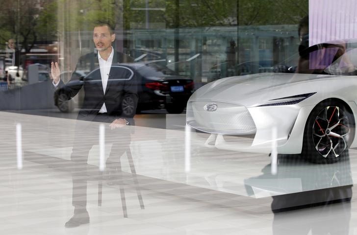 © Reuters. Roland Kruger, President of Nissan's Infiniti Motor Company, is seen through a glass wall as he speaks next to an Infiniti Q Inspiration concept car in Beijing