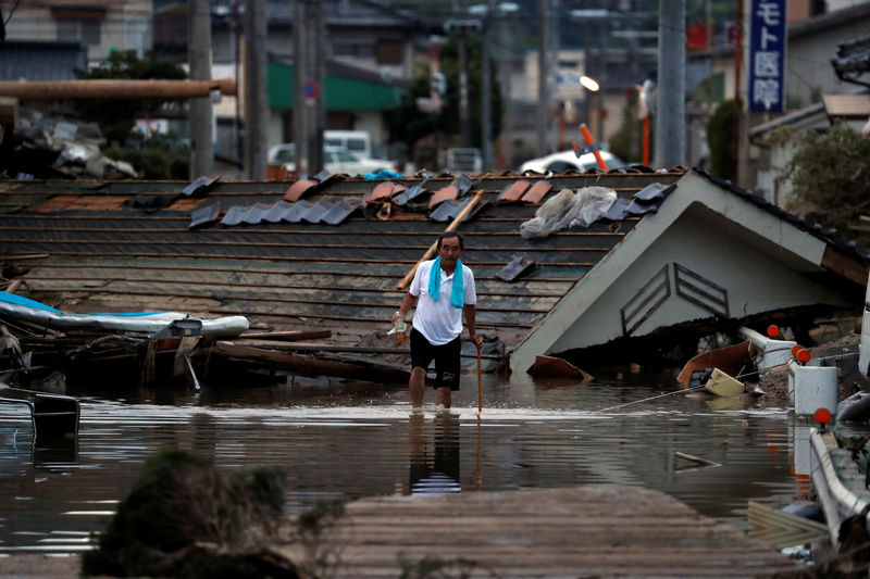 © Reuters. Morador passa por casas destruídas em área alagada na cidade de Kurashiki, no Japão