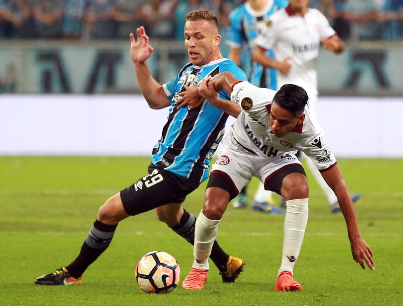 © Reuters. El jugador de Gremio Arthur Melo (izq) lucha por un balón con José Luiz Gómez de Lanus en la final de la Copa Libertadores en Arena do Gremio, Porto Alegre, Brasil