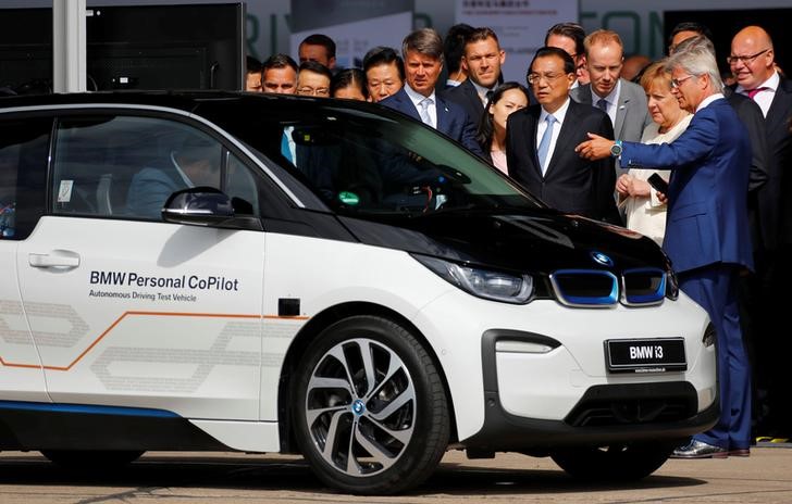 © Reuters. Harald Krueger, CEO of BMW, German Chancellor Angela Merkel and Chinese Prime Minister Li Keqiang attend a presentation for autonomous driving next to a BMW car at Tempelhof airport in Berlin