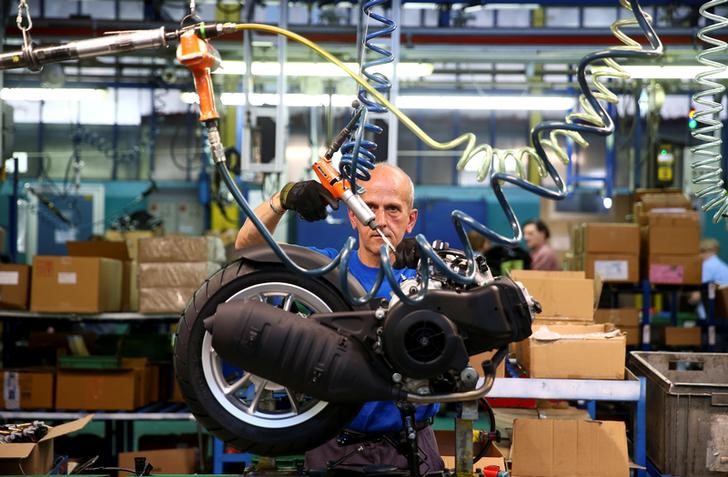 © Reuters. Un operaio al lavoro in una fabbrica che produce motorini
