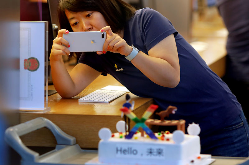 © Reuters. FILE PHOTO: A member of Apple staff takes pictures as new iPhone X begins to sell at an Apple Store in Beijing