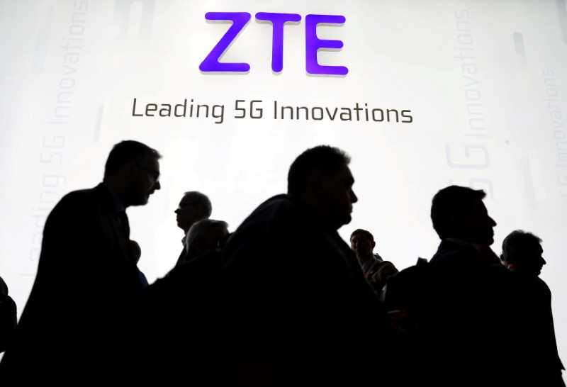 © Reuters. FILE PHOTO:  Visitors pass in front of the ZTE booth at the Mobile World Congress in Barcelona