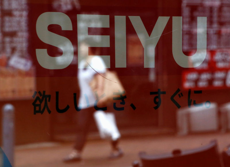 © Reuters. A woman is reflected on a logo of Seiyu at its chainstore in Tokyo