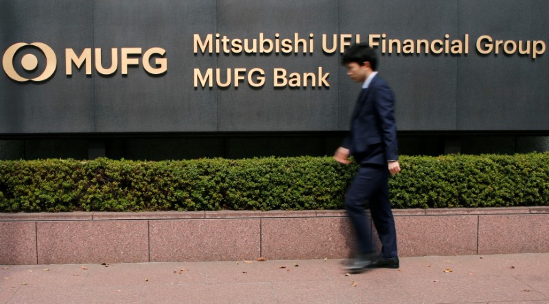 © Reuters. A man walks past a signboard of Mitsubishi UFJ Financial Group and MUFG Bank at its headquarters in Tokyo