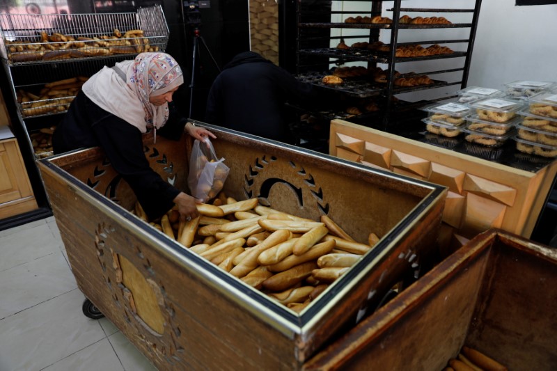 © Reuters. A woman picks up bread in a shop in Tripoli
