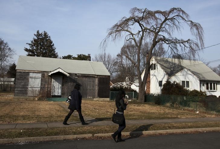 © Reuters. Girls walk by a locked and boarded up home in Brentwood, New York