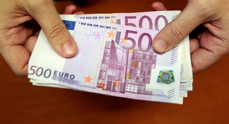 © Reuters. FILE PHOTO: A bank employee holds a pile of 500 euro bank notes in Madrid