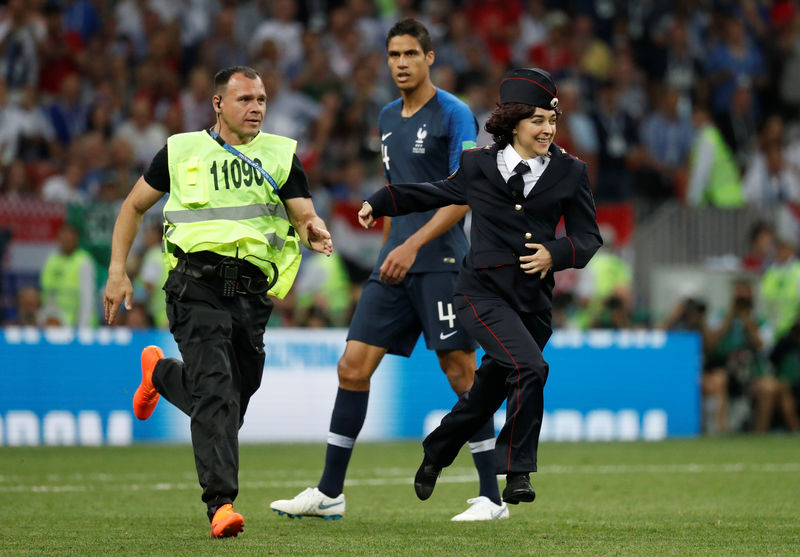 © Reuters. Foto del domingo de un guardia de seguridad persiguiendo a una miembro de la banda Pussy Riot que había invadido el campo de juego en la final del Mundial