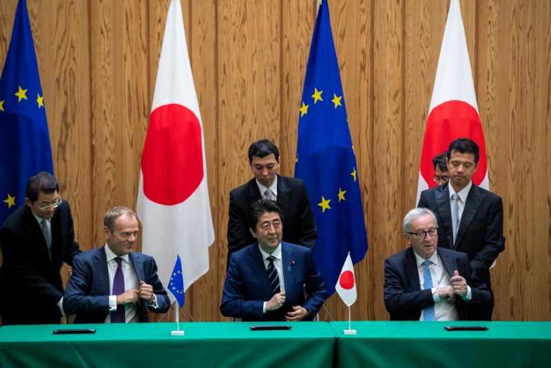 © Reuters. Japanese Prime Minister Shinzo Abe signs a contract with European Commission President Jean-Claude Juncker and European Council President Donald Tusk at the Japanese Prime Minister's office in Tokyo
