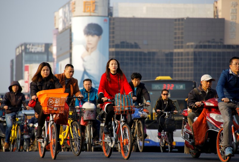 © Reuters. FILE PHOTO: People cross a busy street on bicycles and electric scooters in central Beijing