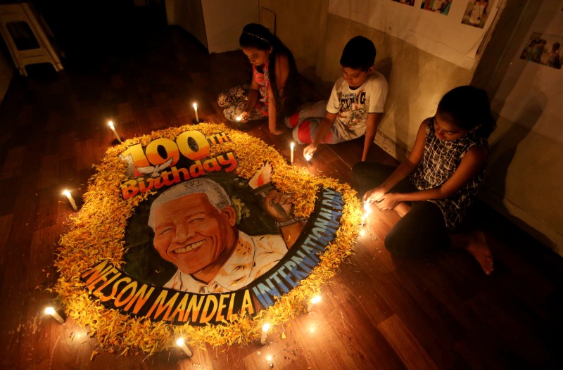 © Reuters. Crianças de Mumbai acendem velas em homenagem ao 100º aniversário de Mandela