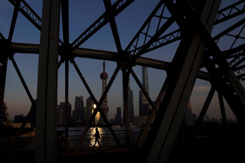 © Reuters. A man walks on a bridge in front of the financial district of Pudong in Shanghai