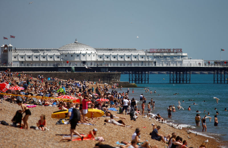 © Reuters. Visitors enjoy the sunshine on the beach by Brighton Pier in Brighton