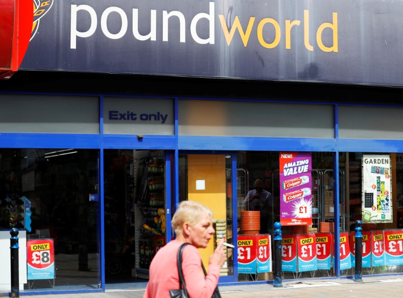 © Reuters. A woman smokes as she passes a branch of Poundworld in Stockport, near Manchester