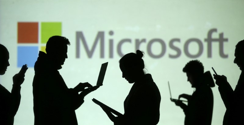 © Reuters. Pessoas utilizam computadores diante de projeção de logo ga Microsoft em foto ilustrativa