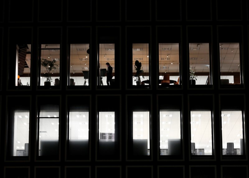 © Reuters. A man is seen at a a commercial building at closing hour at a financial district in Tokyo