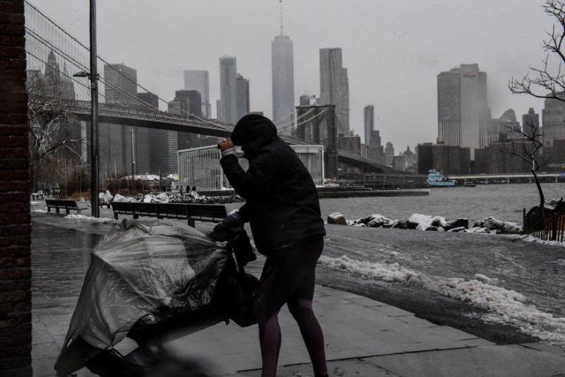 © Reuters. FILE PHOTO: A person walks in the wind during a storm past the Manhattan skyline in the Brooklyn borough of New York City
