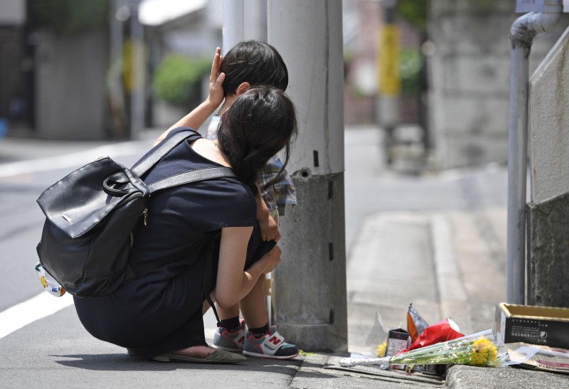 © Reuters. A mother and her child mourn for Yua Funato in front of an apartment where she died in Tokyo
