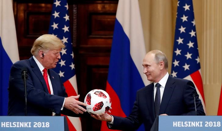 © Reuters. FILE PHOTO: U.S. President Donald Trump receives a football from Russian President Vladimir Putin as they hold a joint news conference after their meeting in Helsinki