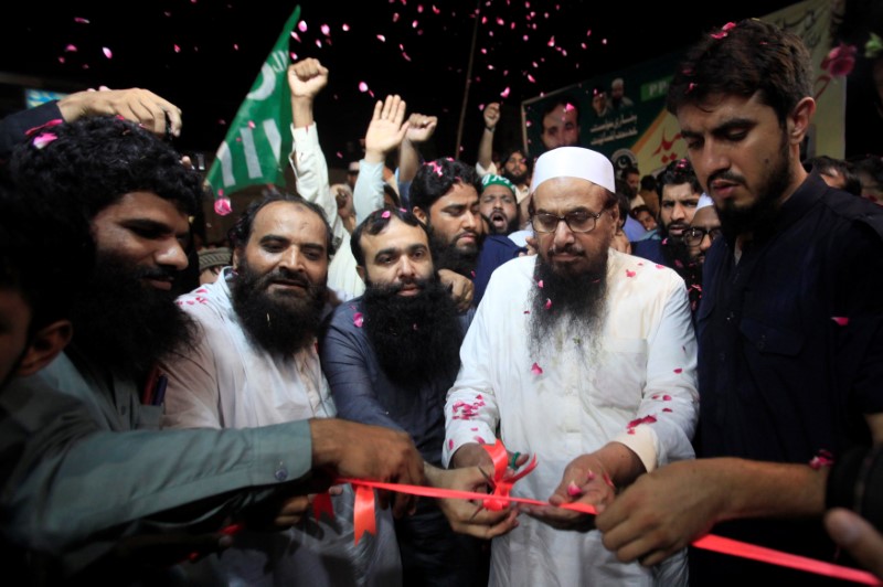 © Reuters. Hafiz Muhammad Saeed, chief of the Islamic charity organisation Jamaat-ud-Dawa (JuD), cuts a ribbon to inaugurates an election office of the newly formed political party Allah-o-Akbar Tehreek, in Lahore