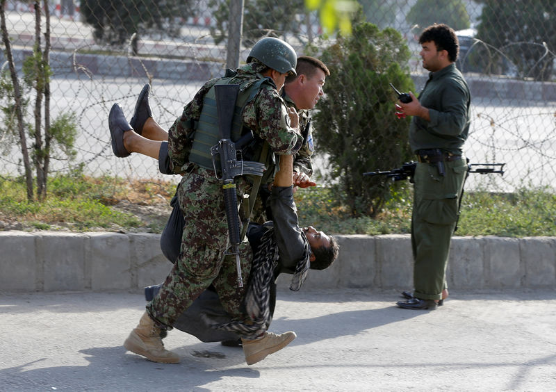 © Reuters. Afghan soldiers carry an injured man after a blast in Kabul